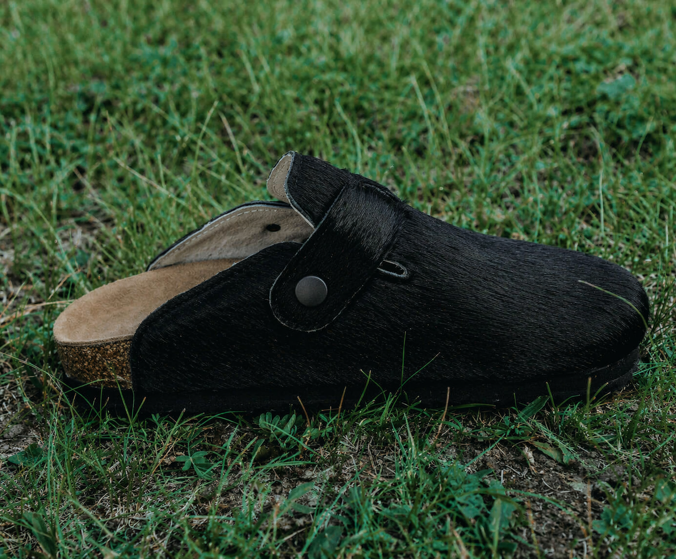 MOGSki handcrafted natural black cowhide fur clogs on grass, luxury year-round footwear from Inner Mongolia artisan made