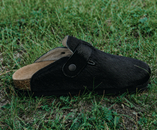 MOGSki handcrafted natural black cowhide fur clogs on grass, luxury year-round footwear from Inner Mongolia artisan made
