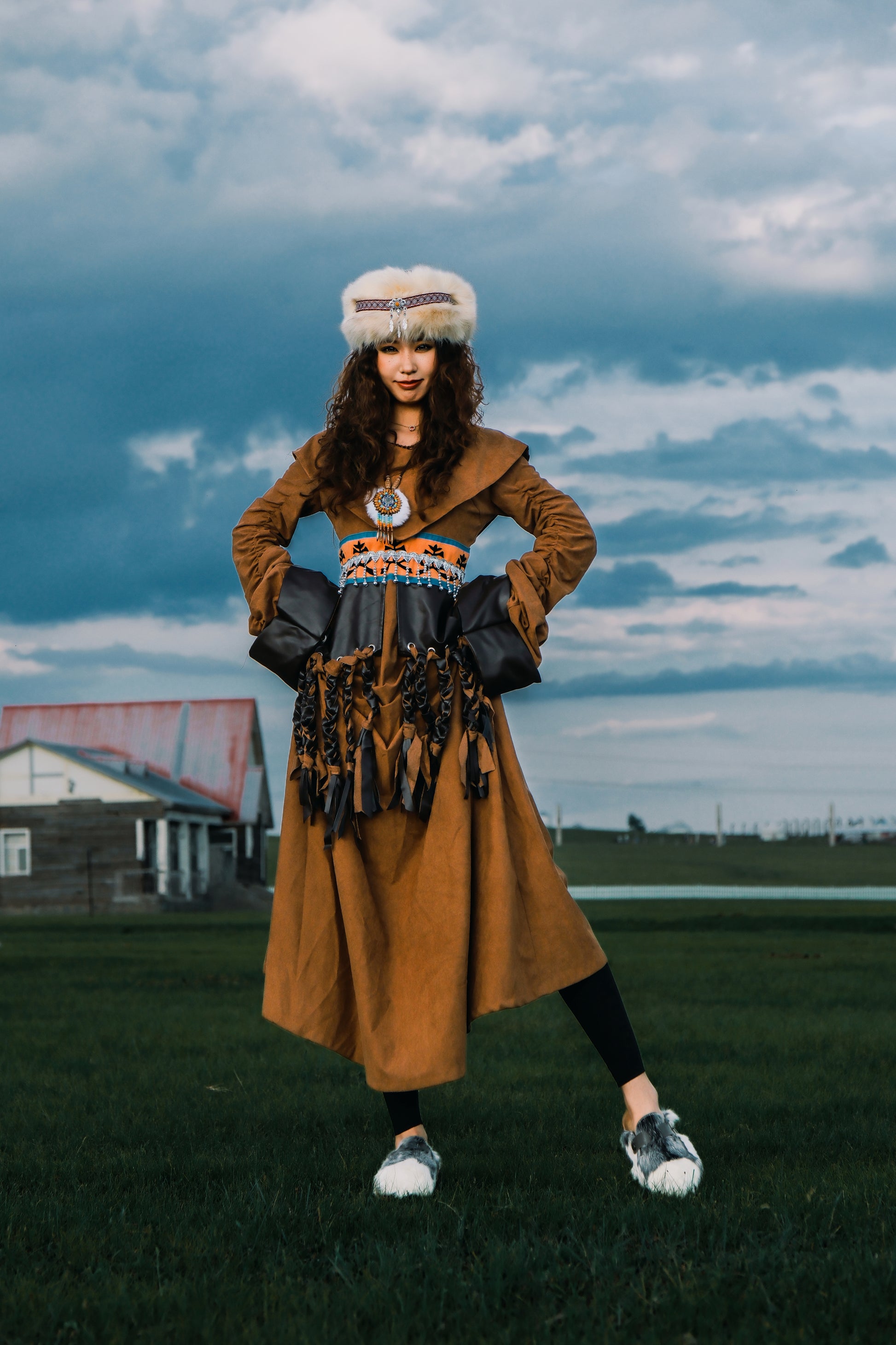 MOGSki handcrafted fur boots worn with golden dress in open landscape, luxury natural hide Mongolian footwear lifestyle shot